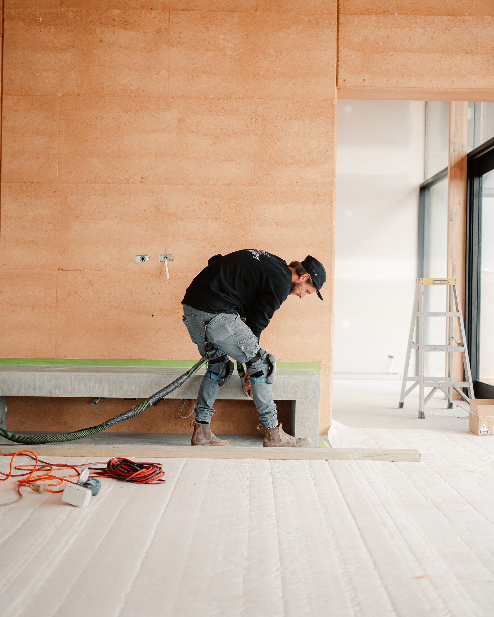 Tradesperson polishing a concrete bench against a rammed earth wall