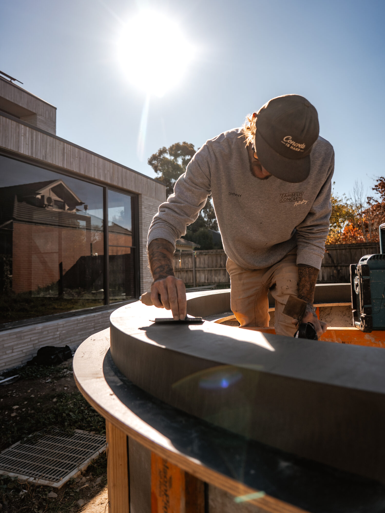 Johnny troweling a curved concrete element in a sunlit backyard