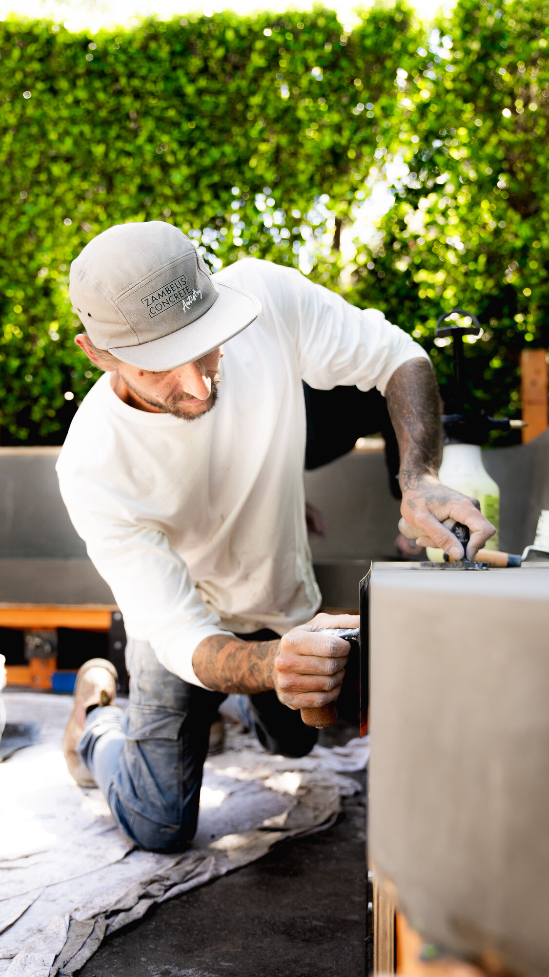 Artisan chamfering an outdoor concrete bench corner by hand