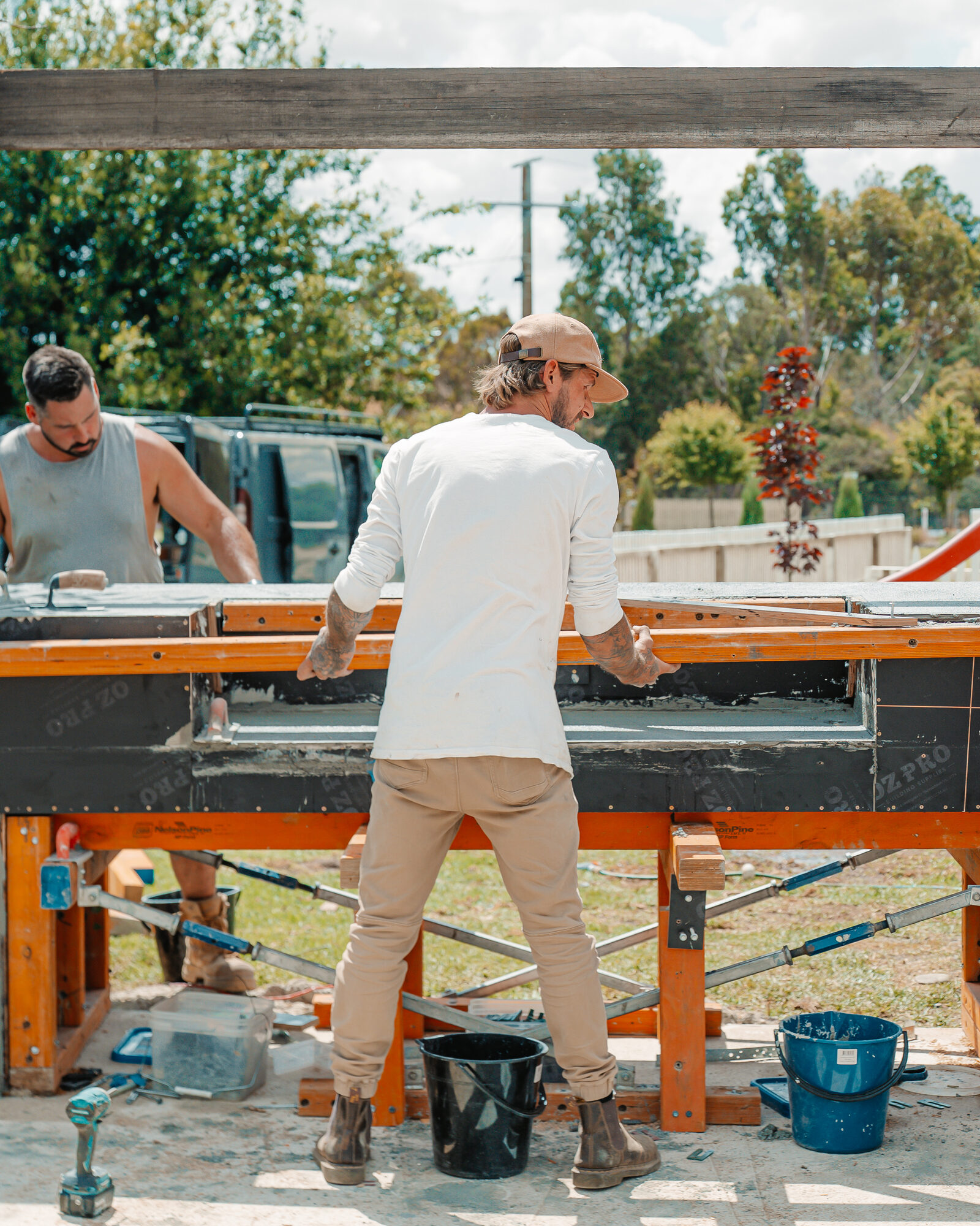 Workers screeding concrete in an orange form outdoors