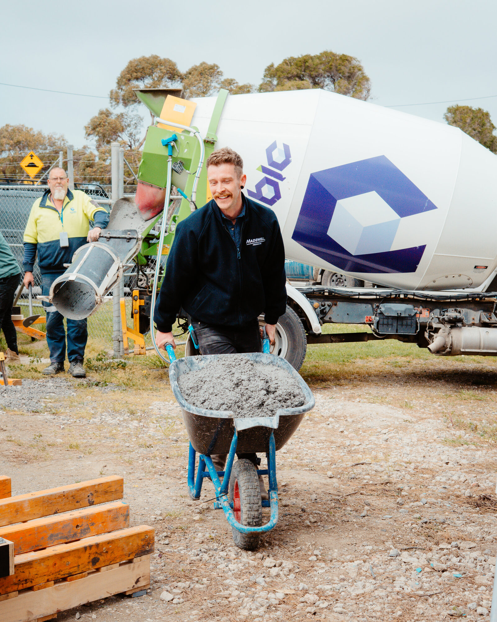Worker wheelbarrowing wet concrete from a mixer truck