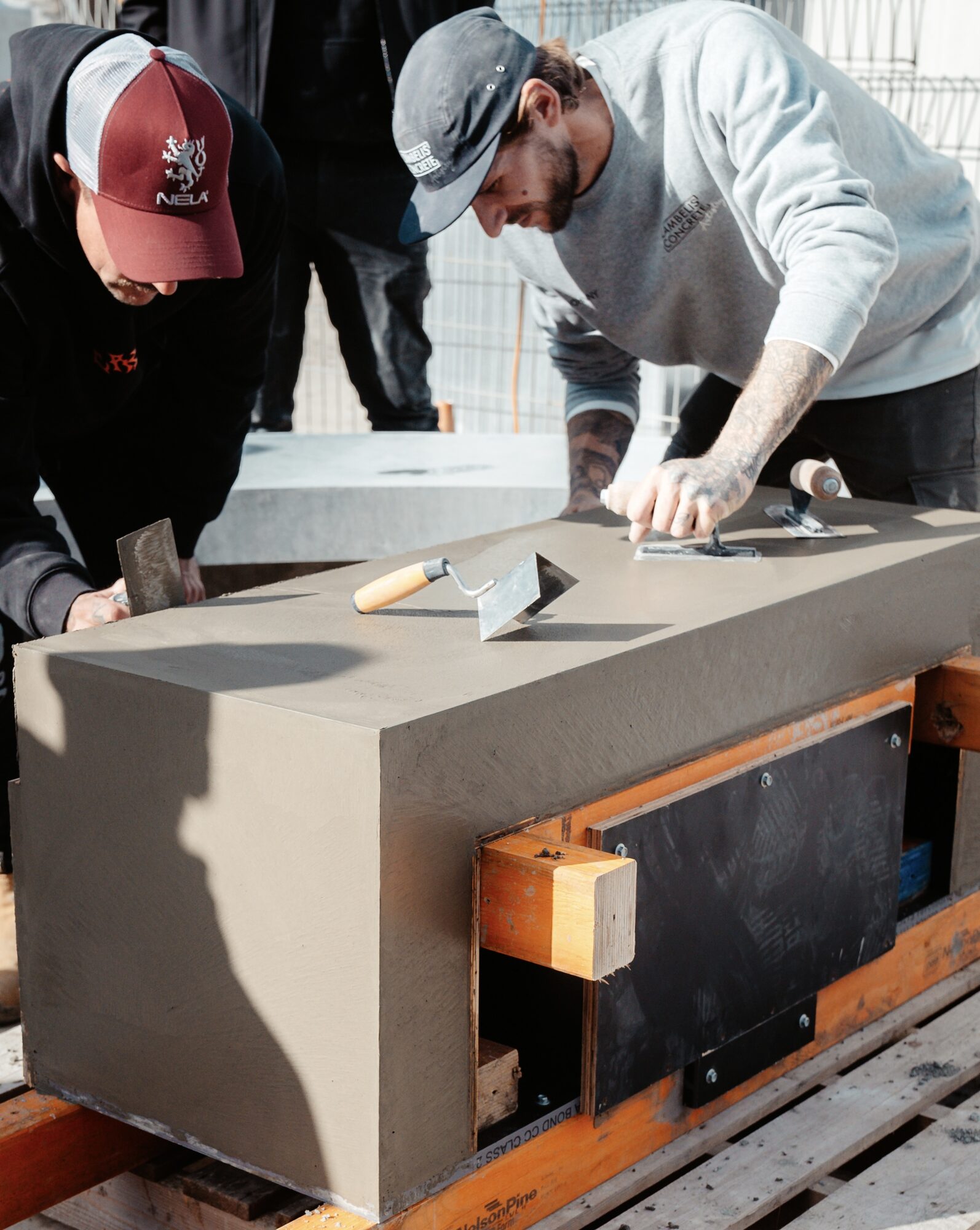 Two trainees troweling a large concrete casting on a pallet